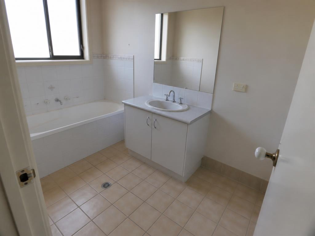 Dated bathroom with beige floor tiles, photographed on a phone